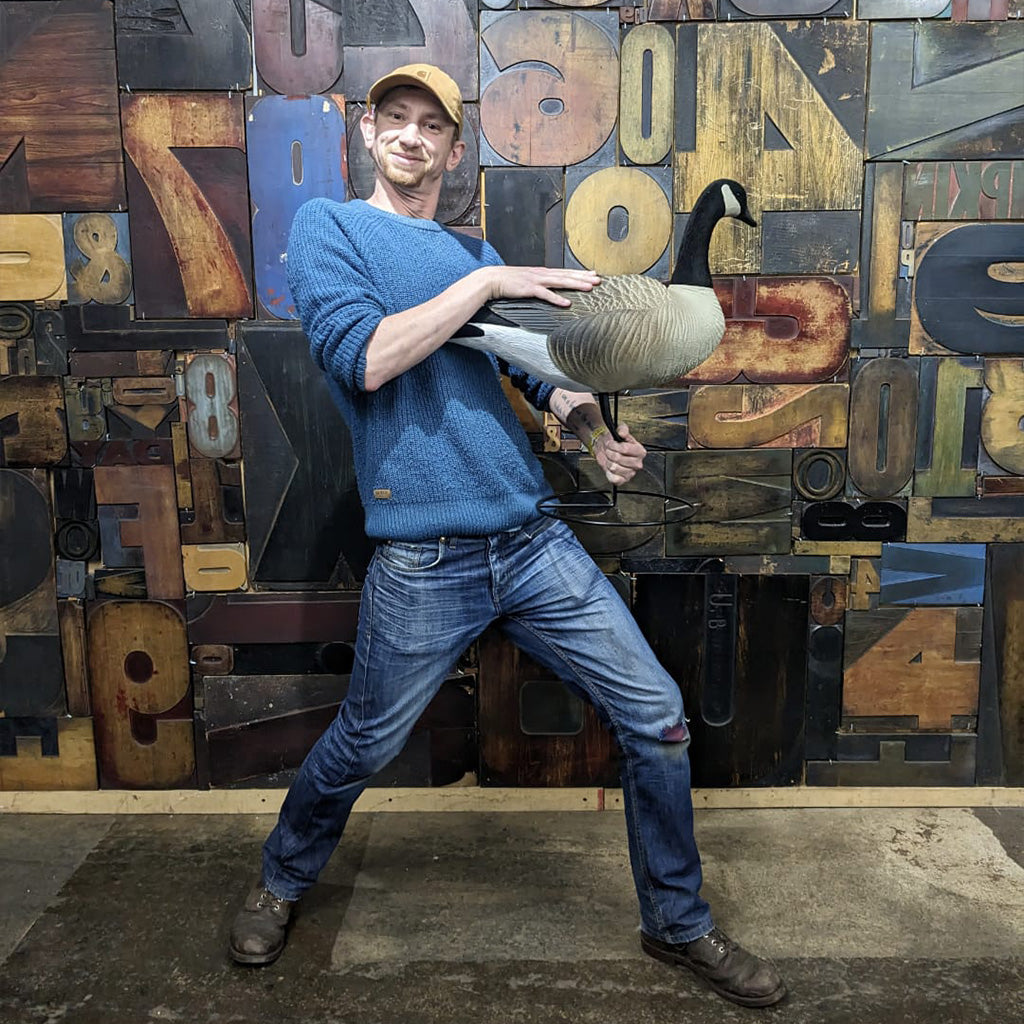 Person holding a goose in front of a wall made of large wooden letters.